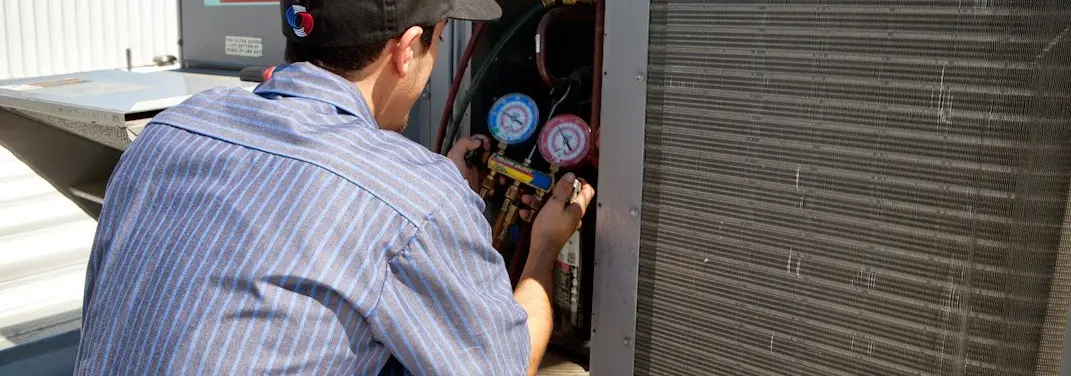HVAC technician servicing a condenser unit in Rexburg